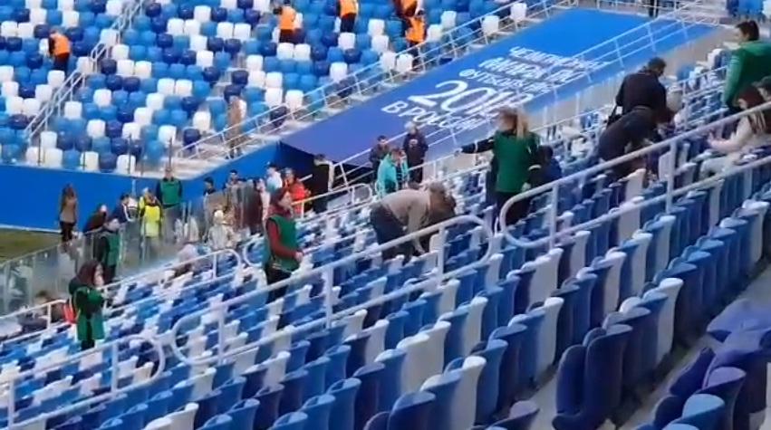 Первые зрители на стадионе Нижний Новгород протирают сидения от строительной пыли